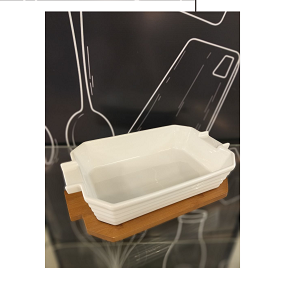 White oval porcelain casserole 32 cm with integrated handles and dark wooden base combining elegance and practicality for direct serving from oven to table 
