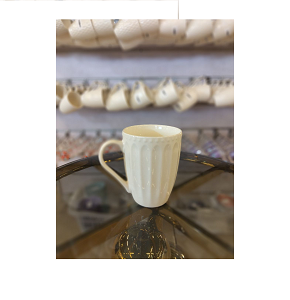 Creamy porcelain mug with classic textured design and handle 
