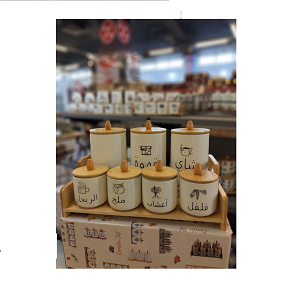 Set of 7-piece creamy porcelain spice jars with natural light wooden lids with conical handles decorated with small colorful floral patterns containing 3 tall and 4 short jars arranged on a matching w