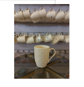 Creamy porcelain mug with textured design and comfortable handle 
