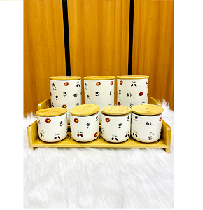 Set of 7-piece creamy porcelain spice jars with natural light wooden lids with conical handles including 3 tall and 4 short jars placed inside a matching wooden tray ideal for kitchen organization 
