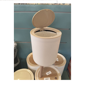 Elegant Scandinavian simple design trash bin with matte white cylinder resting on three light wooden angled legs for stability with round wooden lid equipped with one-touch push button for easy openin